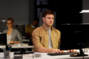 Ein Mann in einem ockerfarbenen Hemd arbeitet am Computer.