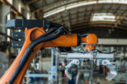 Automatisierter Arm eines Roboters in einer Industriehalle.