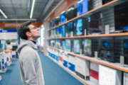 Ein junger Mann betrachtet in einem Geschäft die Regale mit Fernsehgeräten.