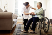 Eine Gesundheitspflegerin spricht mit einer Person im Rollstuhl.