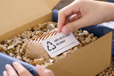 Ein Etikett in einem Pappkarton mit der Aufschrift 100% recycelbar und wiederwendbar.