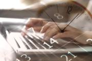Eine Uhr, Zahlen und eine Person, die etwas auf der Computertastatur schreibt