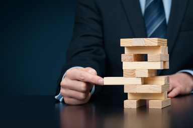 A person forms a tower with wooden sticks and tries to remove one of them.