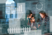 Three people talking in front of pictograms of statistical data.