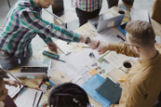 Two young men fist-bump at work