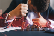 A man hunched over a table displaying a declining graph.