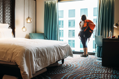A woman with a hiking backpack in a hotel room.