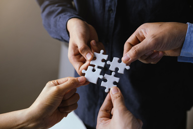 Four people each holding a puzzle piece.