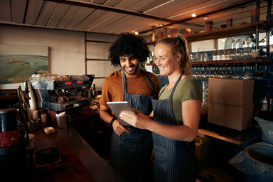 Two baristas consulting a notepad.