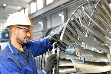 A worker in front of a turbine.