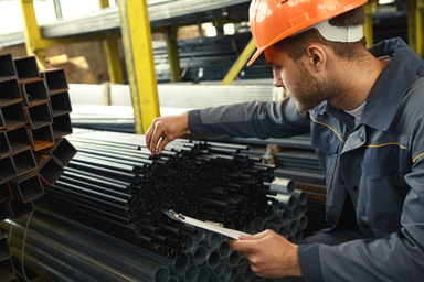 A worker examining thin metal cylinders.
