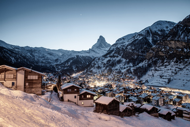 A winter landscape with chalets at the foot of the Matterhorn.