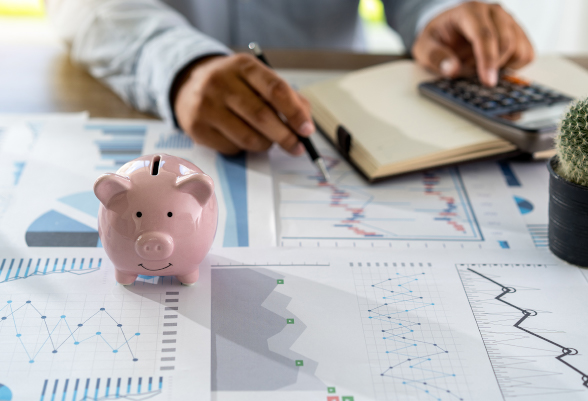 A man performs calculations using a calculator. In the foreground is a piggy bank