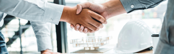 Two men in suits shake hands.