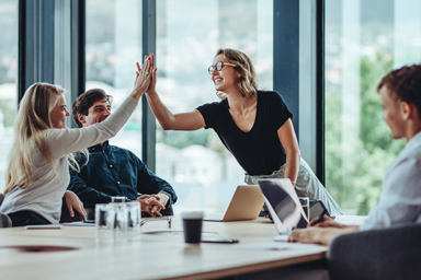 Two people slap hands in a professional environment.