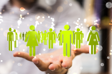 A hand is holding stickers of green men and women