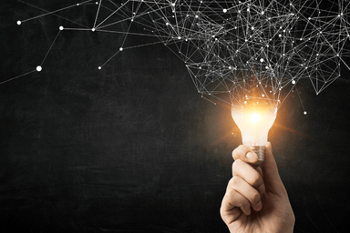 A hand holds a lightbulb with the top splitting into lines and dots