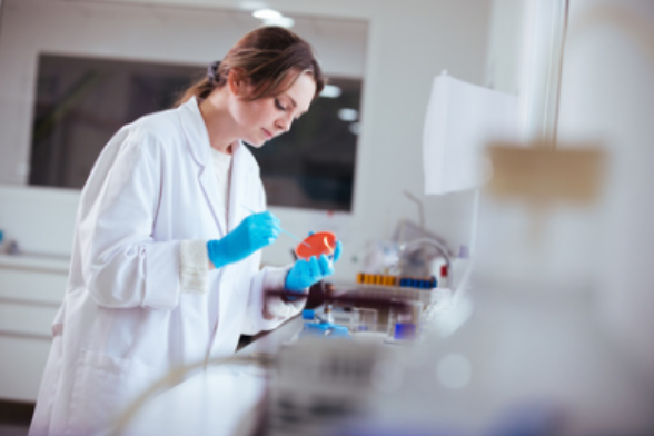 Une chercheuse en blouse blanche travaille dans un laboratoire.