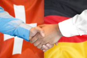 Poignée de main devant les drapeaux suisse et allemand.