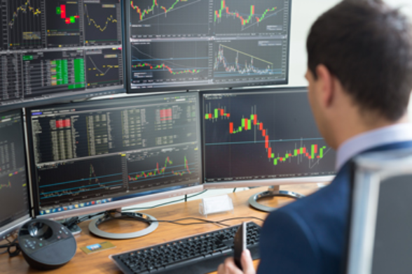 Un homme analyse plusieurs écrans avec les cours de la bourse.