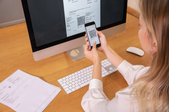 Une femme scanne un code qr devant un PC