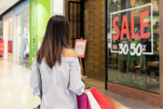 Une femme devant une vitrine portant l’inscription «Sale 30-50%».