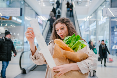 Une femme avec un long ticket de caisse dans un supermarché.