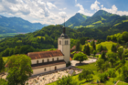 Eine Kirche in einer von Bergen umgebenen grünen Landschaft.