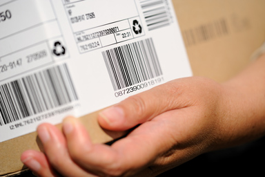 Une personne porte un carton avec une étiquette d’envoi.