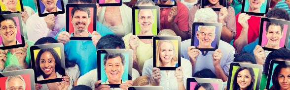 Un groupe de personnes tiennent devant leur tête des tablettes tactiles affichant le visage d'autres personnes.