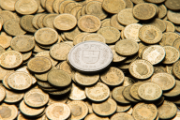 Decine di monetine da cinque centesimi e una moneta da un franco.