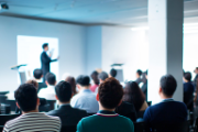 Un folto pubblico assiste a una conferenza.