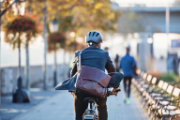 Un uomo, con una borsa e un completo da ufficio, sulla sua bicicletta.