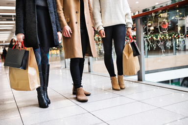 Tre persone camminano in un centro commerciale decorato per il Natale.