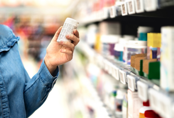 Un consumatore prende una scatola di medicinali dallo scaffale di un negozio.